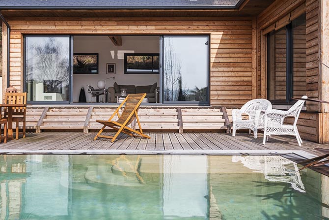 Maison bois. De la piscine et terrasse à l'intérieur